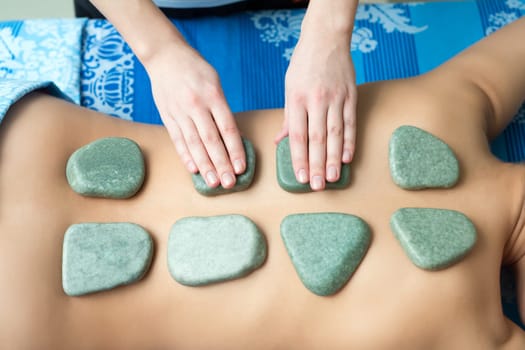 Massage. Top view of hot spa stones on girl's back, close-up