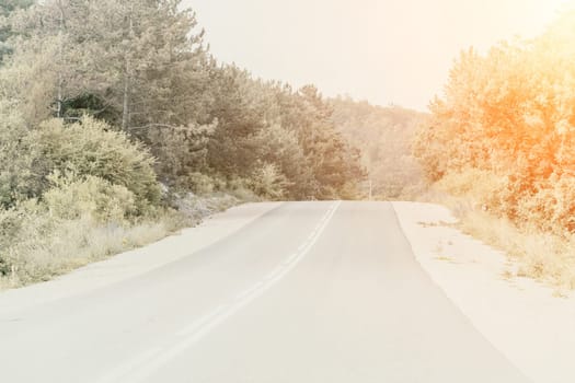 A road with a car driving down it. The road is covered in snow and the trees are bare