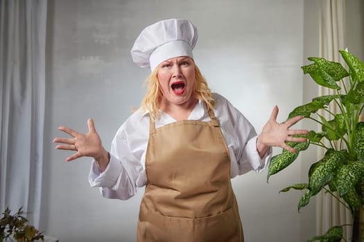 A fat funny female cook in a hat and apron poses in the kitchen and takes selfie. Good cooking and body positive