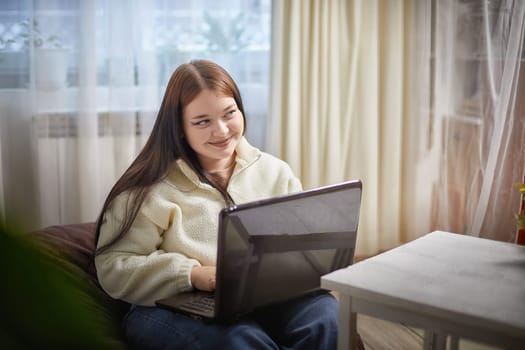 Fashionable young overweight plump female freelancer with portable computer, typing, working remotely from home. Brunette plus size girl using laptop