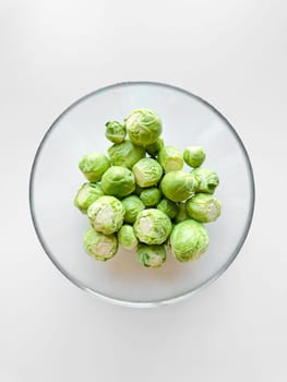 Bowl of raw Brussels sprouts on white surface. Fresh green vegetables, healthy eating, vegetarian food concept with copy space. High quality photo