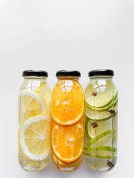 Lemon, orange, and lime detox drinks in glass bottles on white background with copy space. Concept for design and print. High quality photo