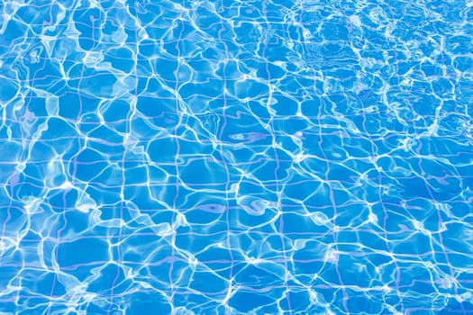 Blue swimming pool water surface and ripple wave background. Summer abstract reflection caustics in swimming pool.