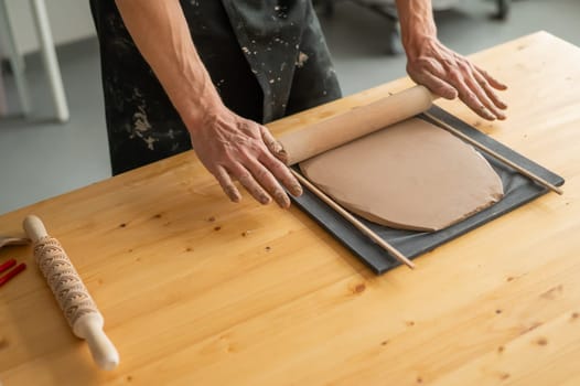 Close-up of potter's hands rolling out clay