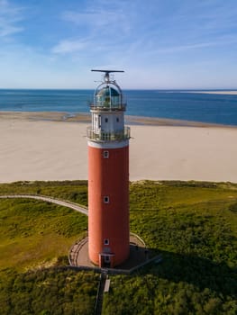 The iconic lighthouse stands tall against the sandy beach, guiding ships with its powerful beam of light amidst a beautiful coastal setting.