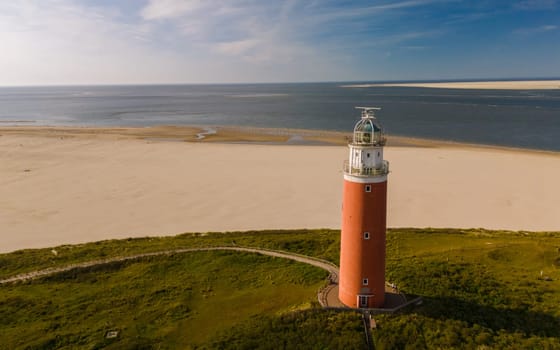 A breathtaking aerial view of a lighthouse standing tall on a sandy beach, guiding ships to safety with its beaming light.