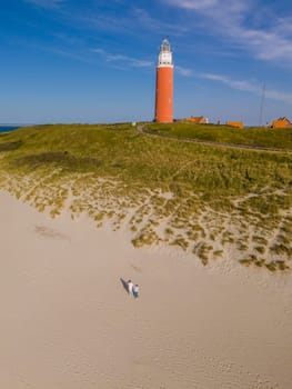 An overhead view of a majestic lighthouse standing tall on a sandy beach, casting its guiding light over the vast expanse of the Texel Netherlands coastline.