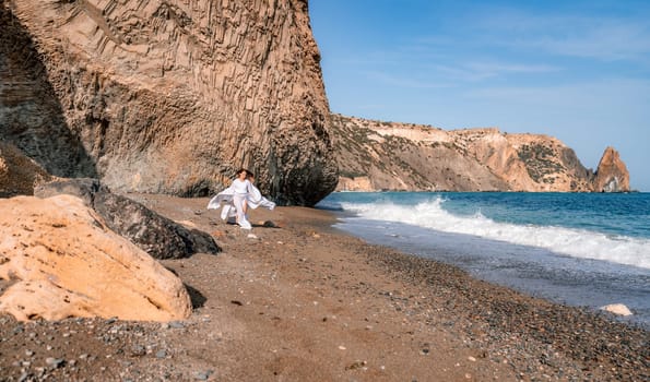 Woman beach white dress flying on Wind. Summer Vacation. A happy woman takes vacation photos to send to friends