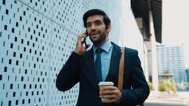 Smart business man using phone to talking about business investment. Happy manager walking at street while talking on smart phone to discuss business plan or marketing strategy or working. Exultant.