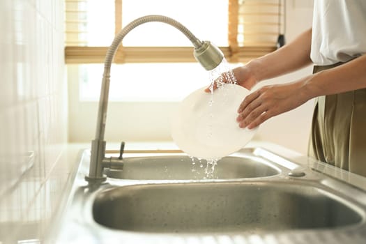 Close up of housewife doing household washing dishes in kitchen sink at home. Housekeeping concept.