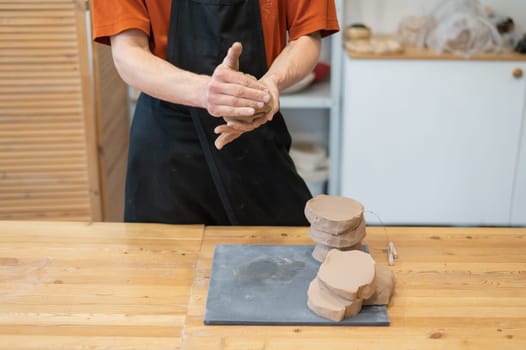 A potter kneads clay before using it in the workshop. Close-up of a man's hands