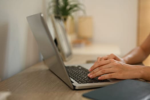 Close up shot of woman hands typing on laptop keyboard working remotely from home.