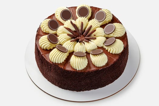 Rich chocolate cake topped with glossy ganache, whipped cream swirls and chocolate branded plaques, divided into individual portions on white background. Confectionery art concept