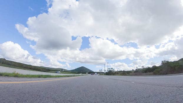 On a clear winter day, a car smoothly travels along Highway 101 near Santa Maria, California, under a brilliant blue sky, surrounded by a blend of greenery and golden hues.