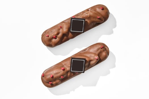 Top view of two milk chocolate-covered pecan bars, sprinkled with dried berry pieces, elegantly presented on white background
