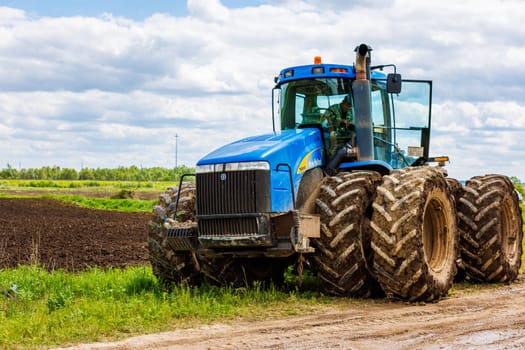 Blue New Holland tractor with double wheels standing near agricultural field at hot sunny day in Tula, Russia - June 4, 2022