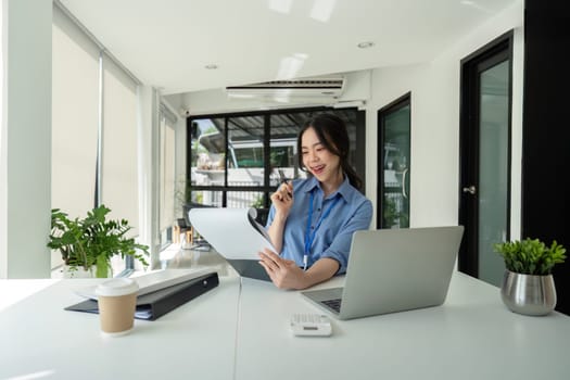 Asian Businesswoman Reviewing Documents at Desk. Concept of Productivity and Professionalism.