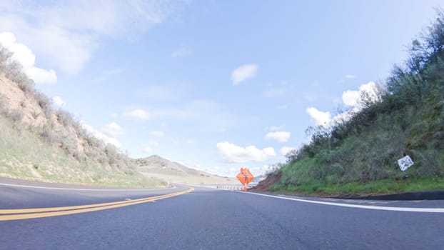 Vehicle is cruising along the Cuyama Highway under the bright sun. The surrounding landscape is illuminated by the radiant sunshine, creating a picturesque and inviting scene as the car travels through this captivating area.