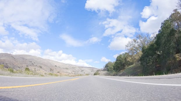 Vehicle is cruising along the Cuyama Highway under the bright sun. The surrounding landscape is illuminated by the radiant sunshine, creating a picturesque and inviting scene as the car travels through this captivating area.