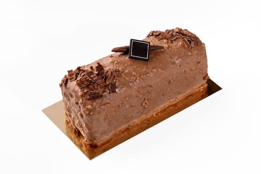 Delicious artisanal loaf cake coated with milk chocolate and nuts glaze, decorated with dark chocolate branding plaque on golden cardboard, isolated on white. Sweet pastries concept