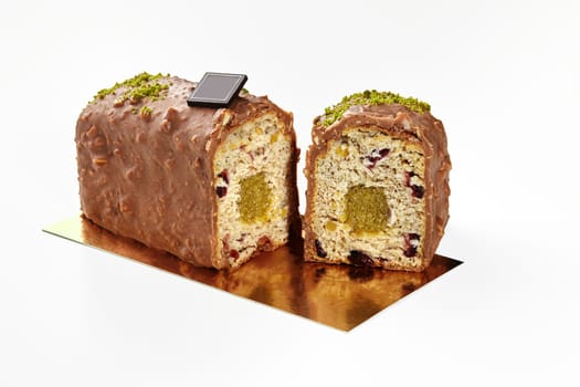 Sliced artisan sweet soft loaf cake with fruit jelly and dried berries glazed with milk chocolate icing and nut crumbs isolated on white background, ideal for delicious snacking