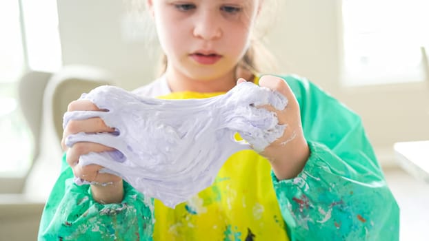 In a modern kitchen, a homeschooled girl is engrossed in creating homemade slime, a fun and educational hands-on project that enhances her creativity and problem-solving skills.