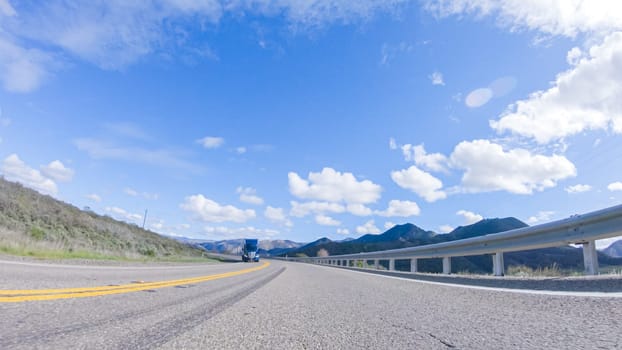 Vehicle is cruising along the Cuyama Highway under the bright sun. The surrounding landscape is illuminated by the radiant sunshine, creating a picturesque and inviting scene as the car travels through this captivating area.