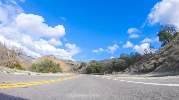 Vehicle is cruising along the Cuyama Highway under the bright sun. The surrounding landscape is illuminated by the radiant sunshine, creating a picturesque and inviting scene as the car travels through this captivating area.