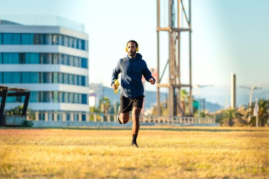 Young latin athlete with headphones training outdoors.