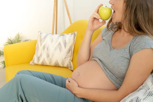 Unrecognizable pregnant woman eating healthy apple. High quality photo