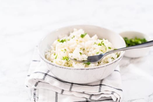 Cilantro Lime Rice. Serving cilantro lime rice garnished with fresh parsley in white ceramic bowls.