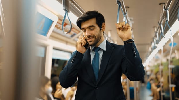 Smart business man phone calling to project manager while standing in train. Professional male leader talking to investor about marketing plan by using phone with blurring background. Exultant.