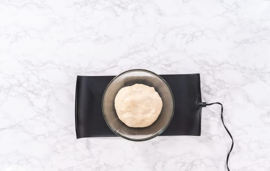 Flat lay. Rising pizza dough in a glass mixing bowl to prepare cinnamon dessert pizza.