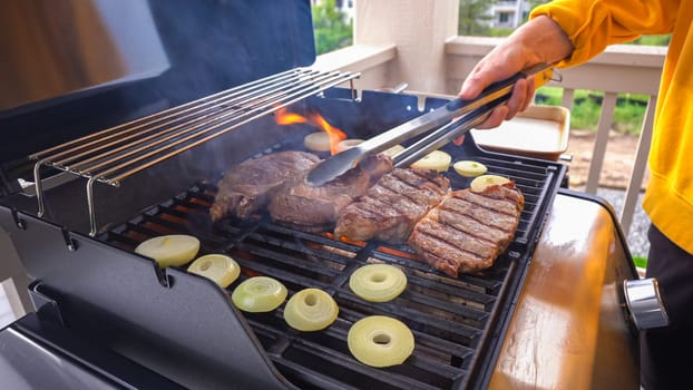 The outdoor two-burner gas grill is put to good use, sizzling with the sound and aroma of ribeye steaks and onion rings being perfectly cooked.