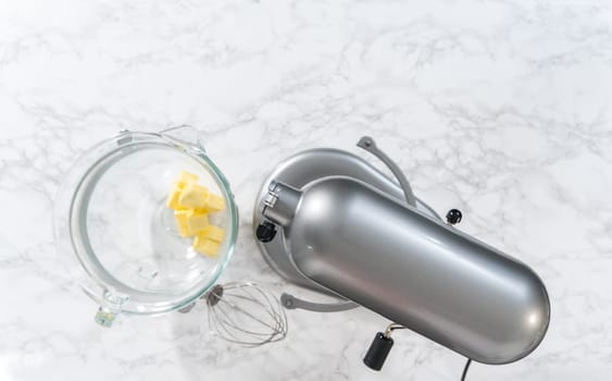 Mixing ingredients in a large glass mixing bowl of kitchen mixer to make eggnog buttercream frosting.