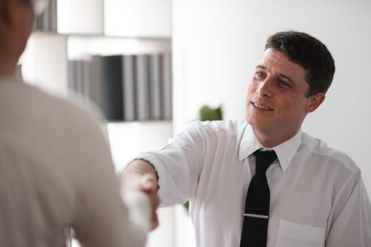 Close-up Businessman shaking hands with colleague in office, concept of agreement and partnership.