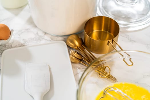 Combining ingredients within a glass bowl, skillfully stirring with a whisk to prepare a delicious vanilla bundt cake.