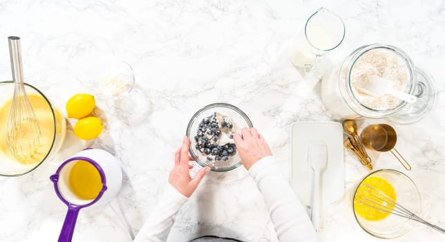 Flat lay. Integrating ingredients in a glass bowl, adeptly stirring with a whisk to craft a tantalizing lemon-blueberry bundt cake.