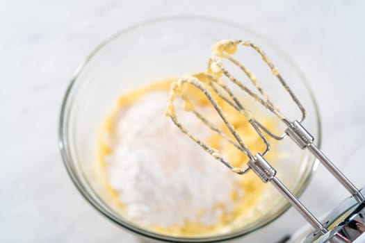 Mixing ingredients in a large glass mixing bowl to make the cream cheese filling for bundt cake.