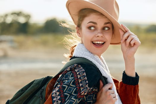 Exploring the desert woman in hat and backpack with car in background