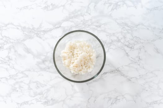 Flat lay. Cilantro Lime Rice. Mixing ingredients in a glass mixing bowl to prepare cilantro lime rice.