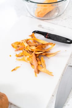 Peeling sweet potatoes with a potato peeler to make oven-roasted sweet potatoes.