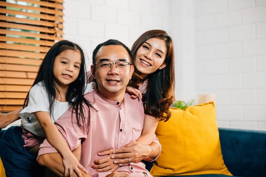 In their modern home a smiling family shares a sweet moment on the sofa highlighting togetherness. Parents daughters and siblings bond laugh and embrace in a joyful family portrait.