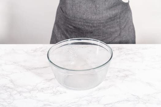 Rising pizza dough in a glass mixing bowl to prepare cinnamon dessert pizza.