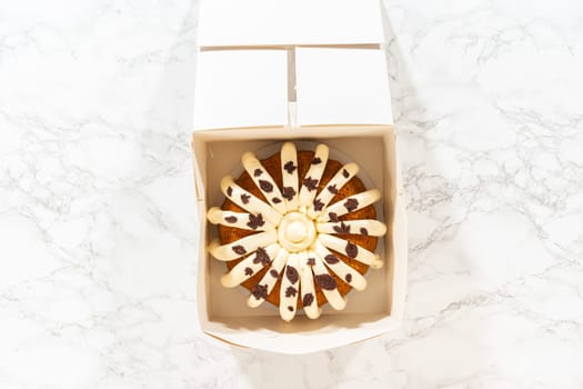Flat lay. Packaging the freshly baked pumpkin bundt cake into a white paper box for gifting.