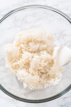 Cilantro Lime Rice. Mixing ingredients in a glass mixing bowl to prepare cilantro lime rice.