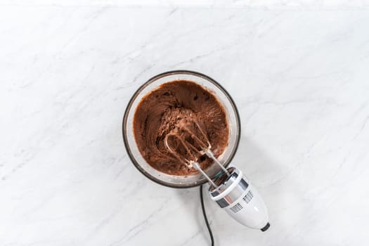 Flat lay. Mixing ingredients in a large glass mixing bowl to bake red velvet bundt cake with cream cheese glaze.