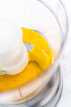 Mixing ingredients in kitchen blender to prepare homemade hollandaise sauce.