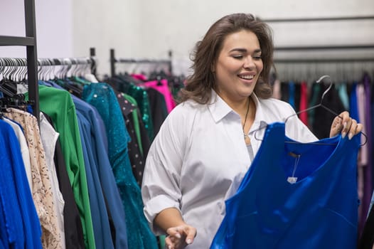 A fat woman chooses clothes in a plus size store