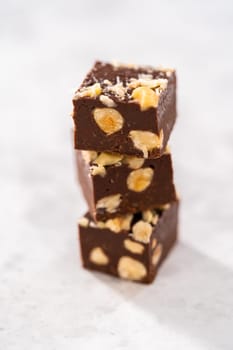 Homemade chocolate hazelnut fudge square pieces stacked on the kitchen counter.